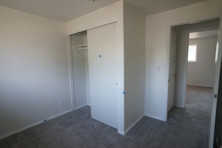Wall-to-wall carpeting, white walls, and a built-in closet with sliding doors