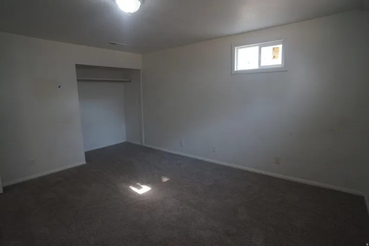 Carpeted room featuring a built-in closet, a ceiling-mounted light fixture, and a single window