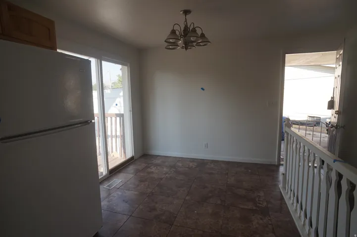 Tiled flooring, overhead light fixture, white baluster railing, sliding glass door, and a paneled entry door