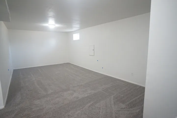 Spacious room featuring gray carpet, white walls, and a single window