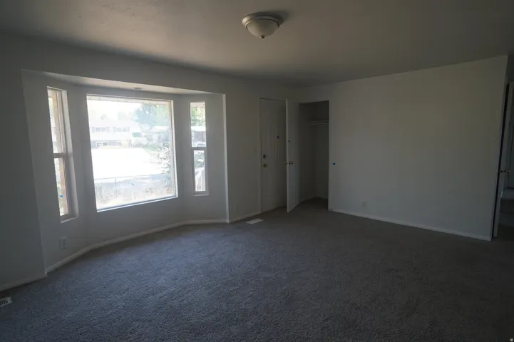 Bay window with multiple panes, gray carpet flooring, white walls, and a ceiling-mounted light fixture