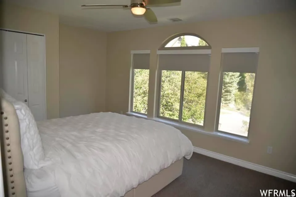 Arched window with two rectangular windows, flush-mount lighting, ceiling fan, and carpeted flooring