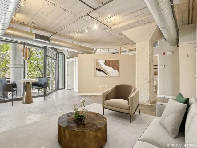 Exposed concrete ceilings and columns, full-height windows, concrete flooring, and visible ductwork
