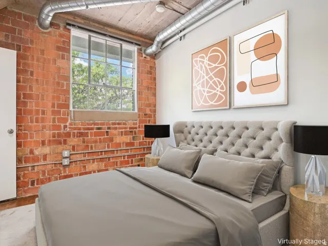 Exposed brick wall, visible ductwork, concrete ceiling, and a large window with multiple panes