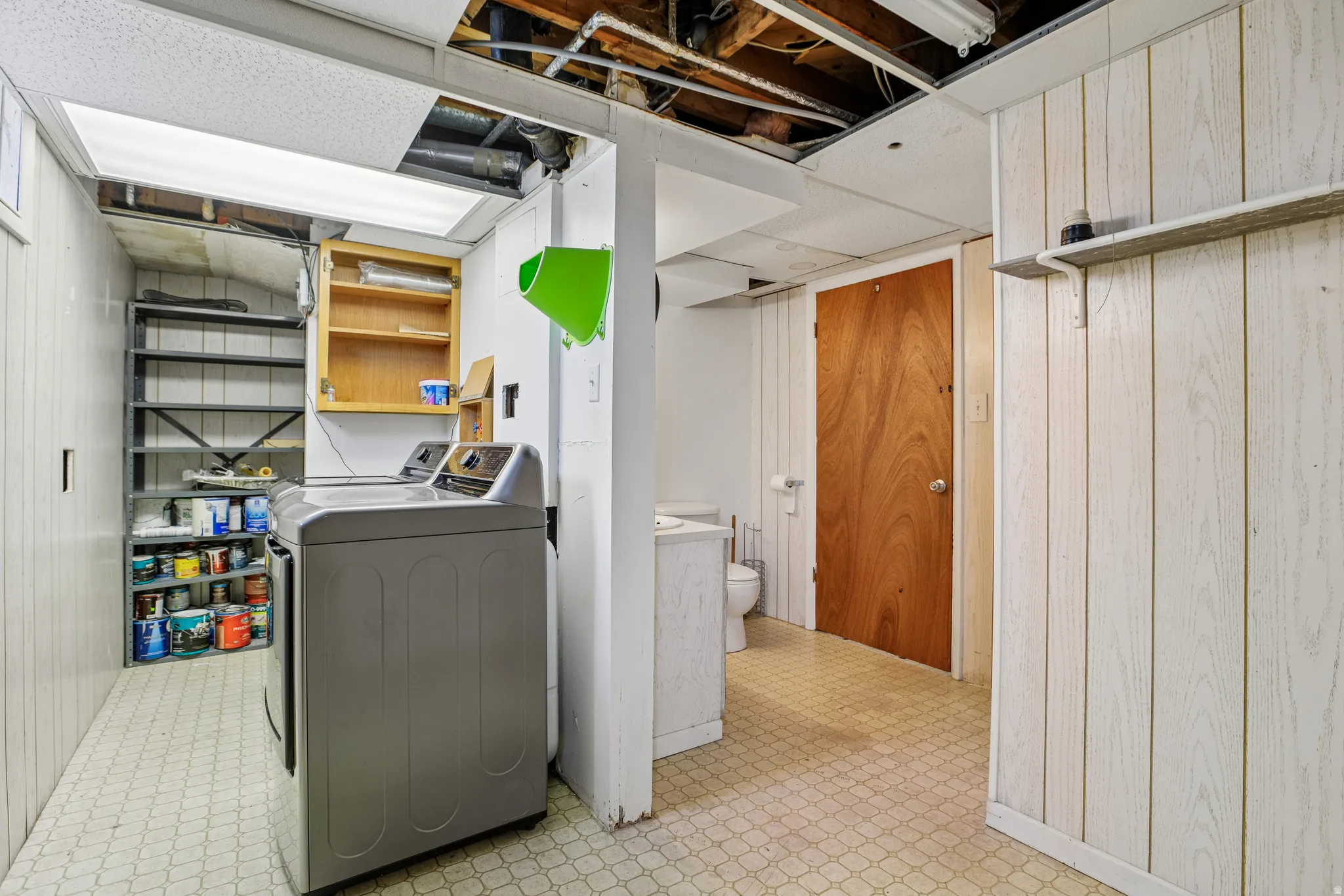 Laundry area with built-in shelving, wood-paneled walls, and a recessed light fixture