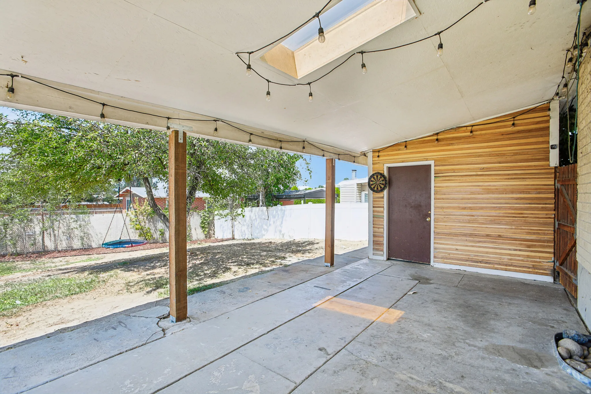 Covered patio featuring a skylight, wood-look siding, and a concrete slab floor