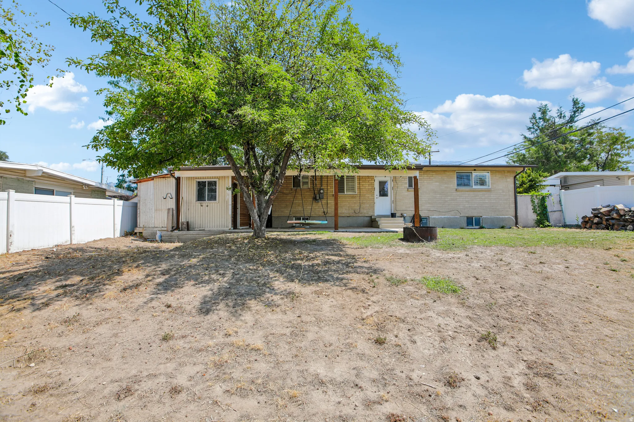 Expansive backyard featuring a mature tree, white privacy fencing, and a detached shed