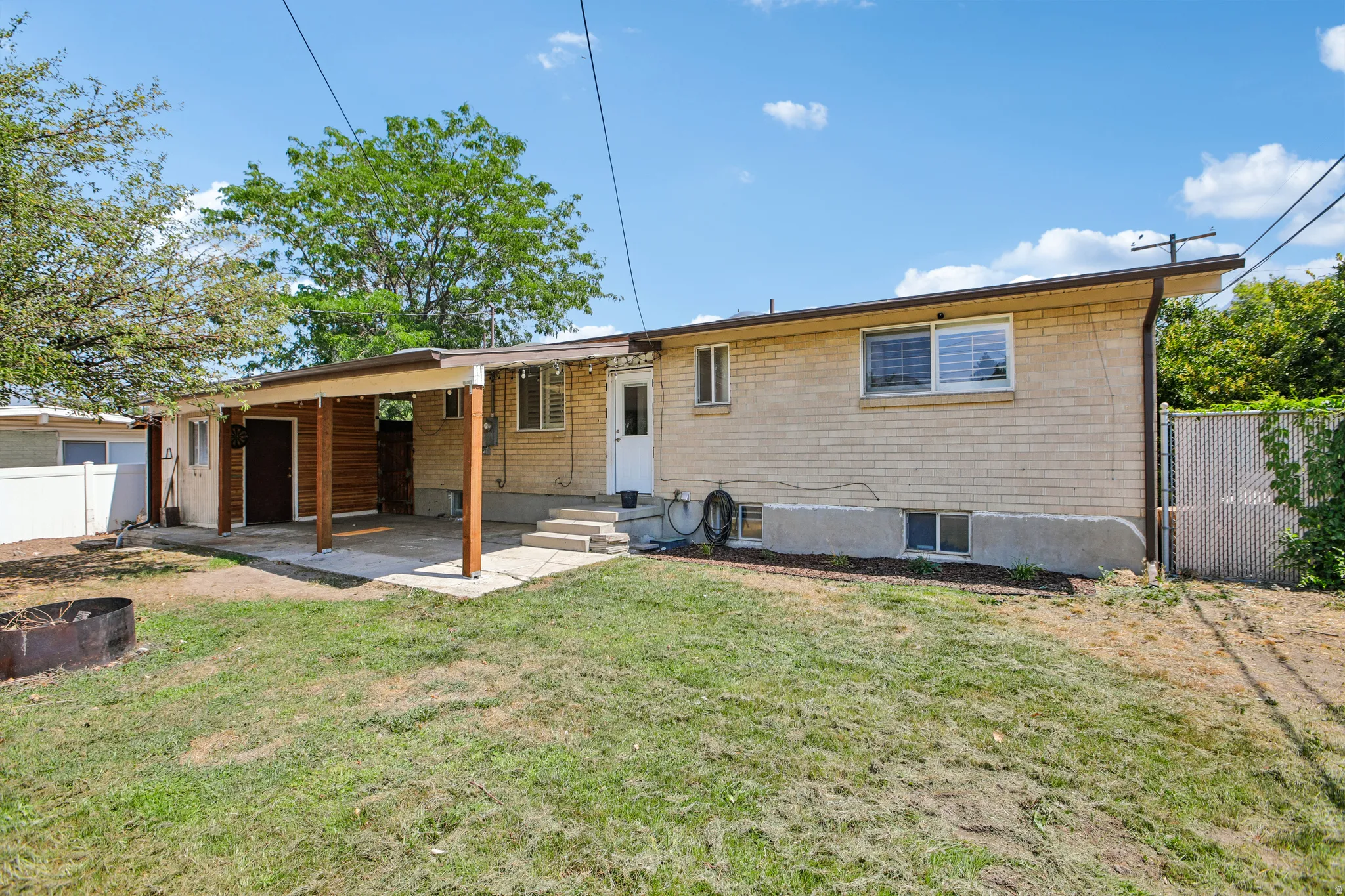 Rear exterior featuring a covered patio with wood-finish supports and ceiling, light brick siding, and multiple windows