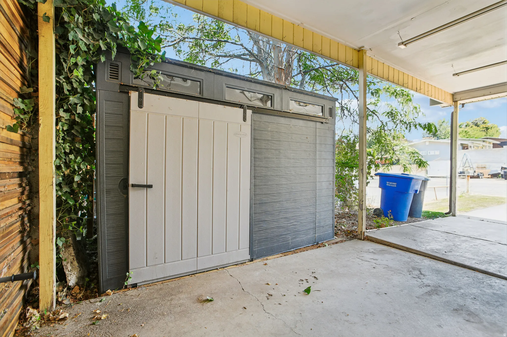 Covered concrete patio with a storage shed featuring a sliding barn door