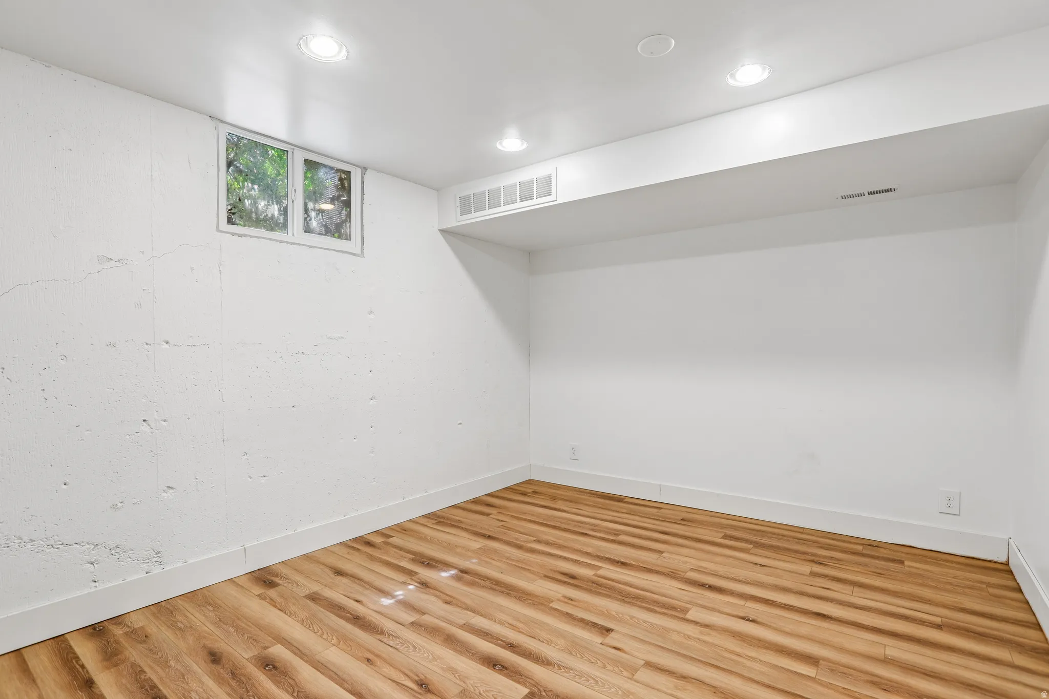 Recessed lighting, wood-finish flooring, and white painted walls