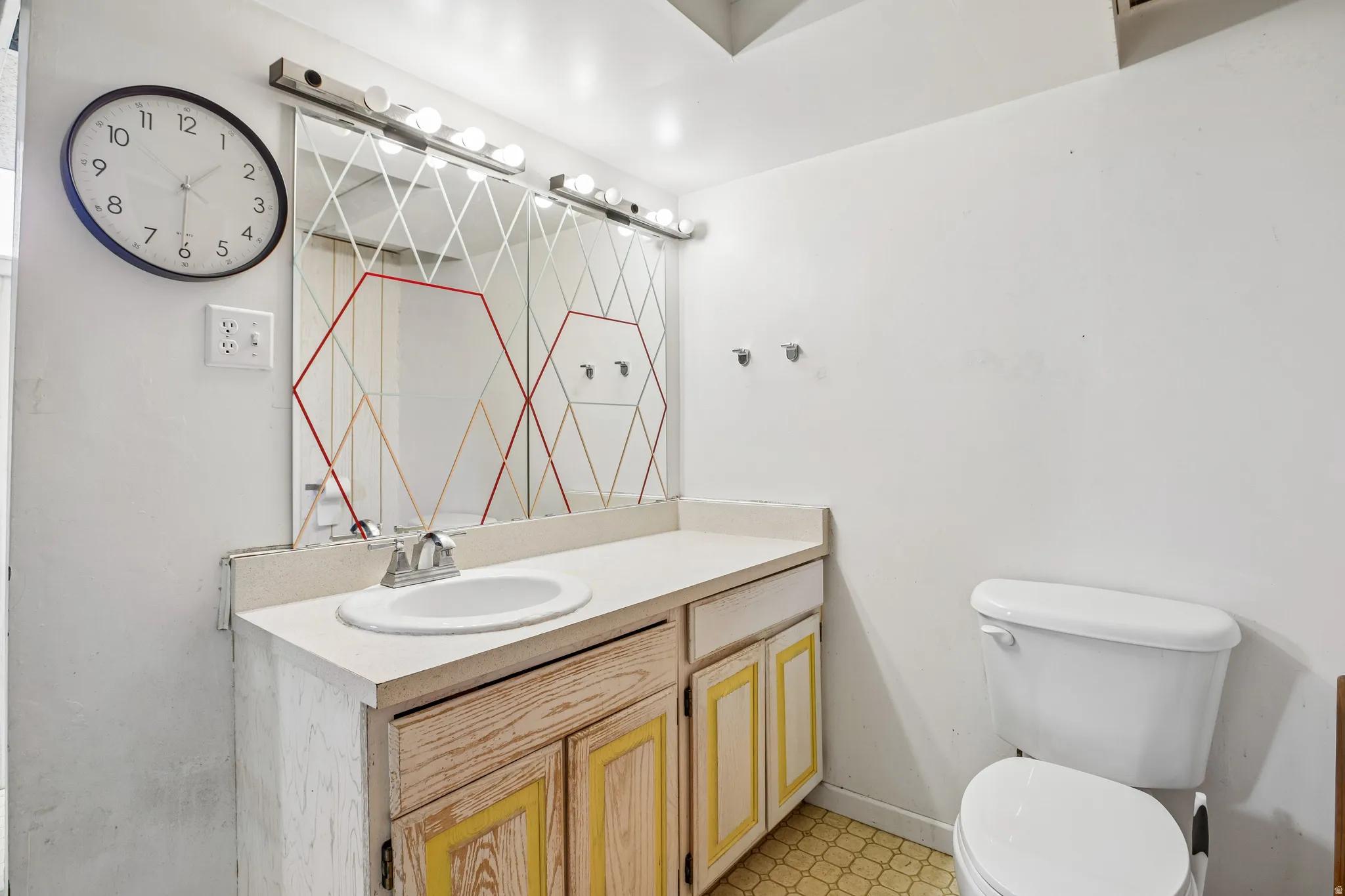 Single basin vanity with cabinet storage, mounted mirror with integrated lighting, and a white toilet