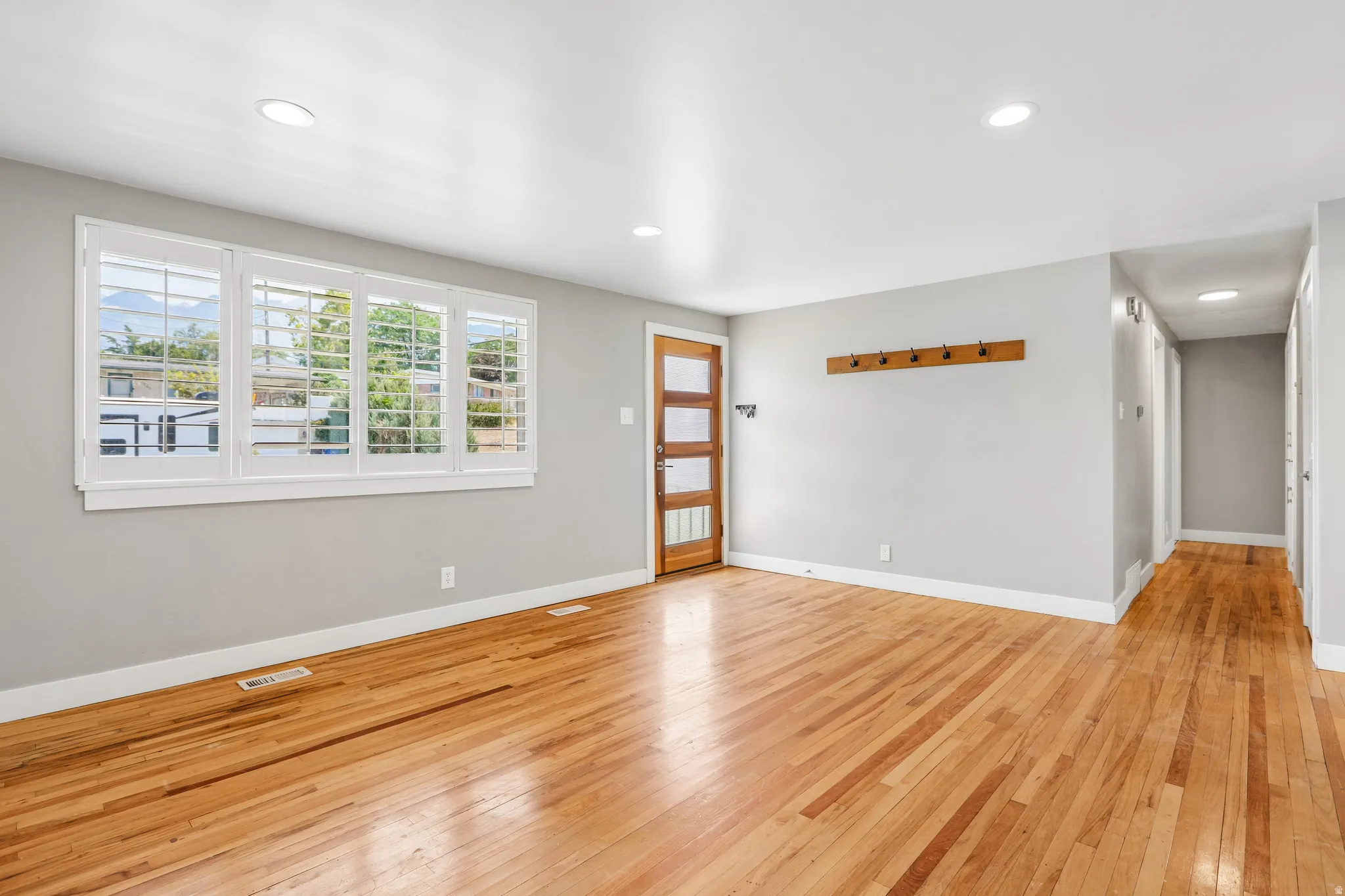 Hardwood flooring, recessed lighting, white trim, light gray walls, and a wood entry door with frosted glass panels