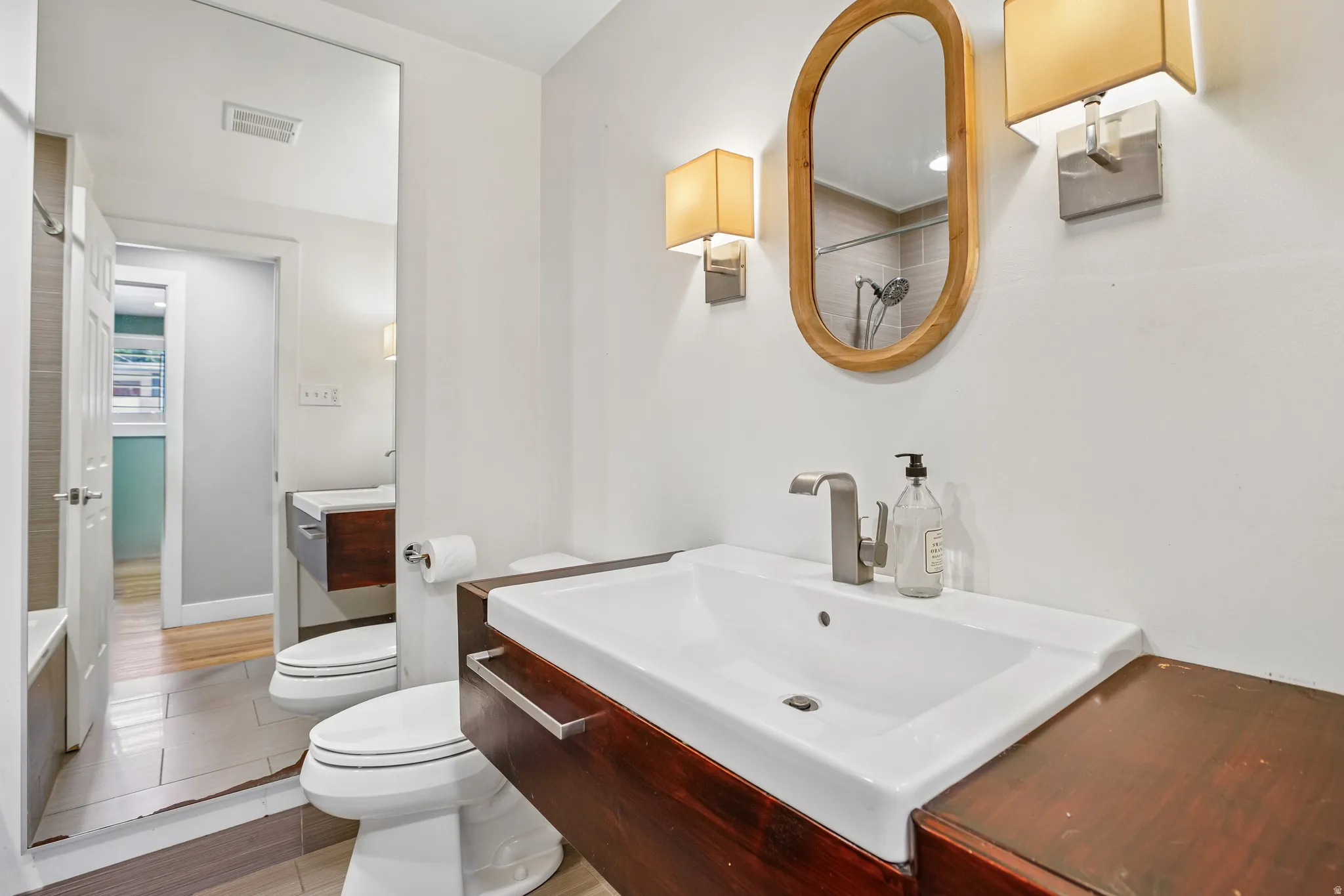 Floating wood-finish vanity with an integrated rectangular sink and brushed nickel faucet