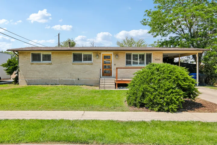 Single-story residence featuring a light brick exterior, a covered entryway, and a carport