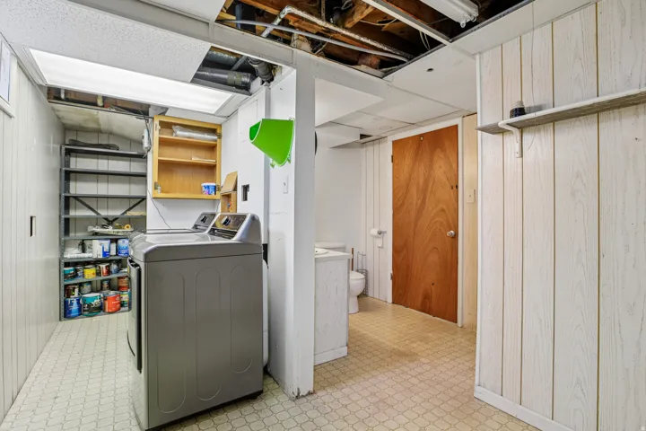 Laundry area with built-in shelving, wood-paneled walls, and a recessed light fixture