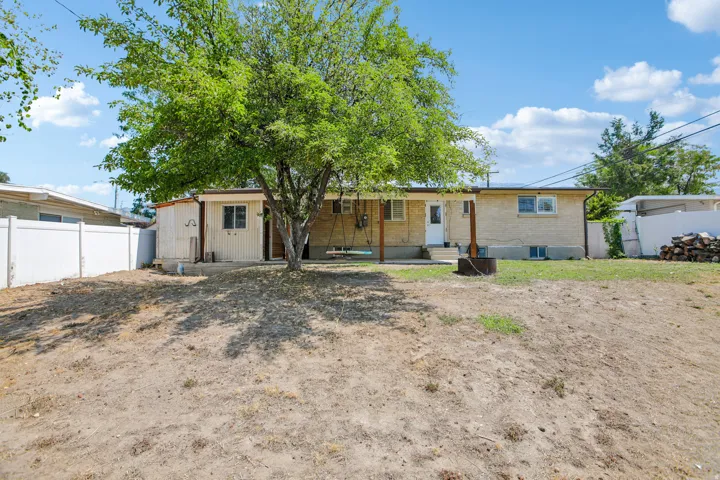 Expansive backyard featuring a mature tree, white privacy fencing, and a detached shed