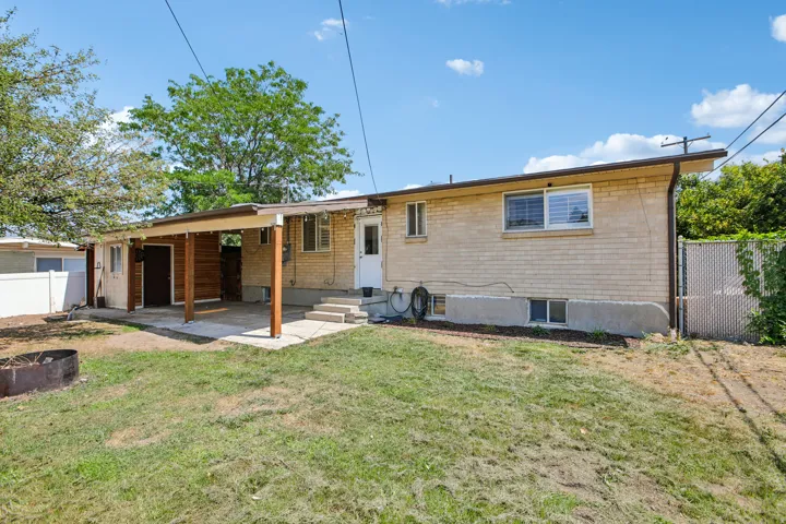 Rear exterior featuring a covered patio with wood-finish supports and ceiling, light brick siding, and multiple windows