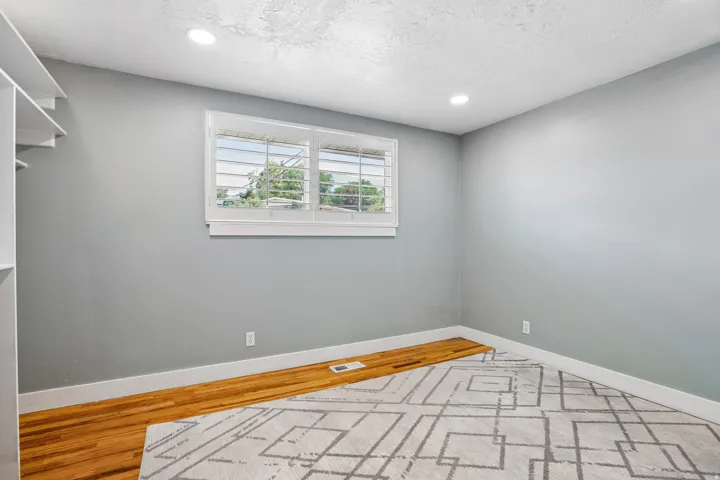 Recessed lighting, wood-finish flooring, white plantation shutters, built-in shelving, and white baseboards