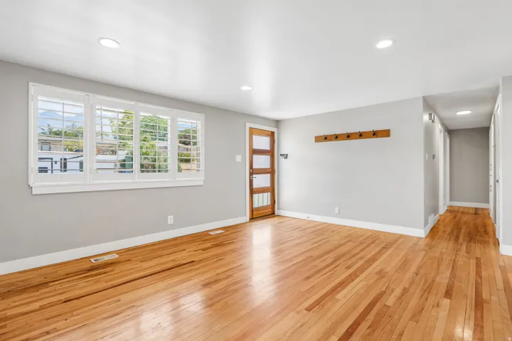 Hardwood flooring, recessed lighting, white trim, light gray walls, and a wood entry door with frosted glass panels