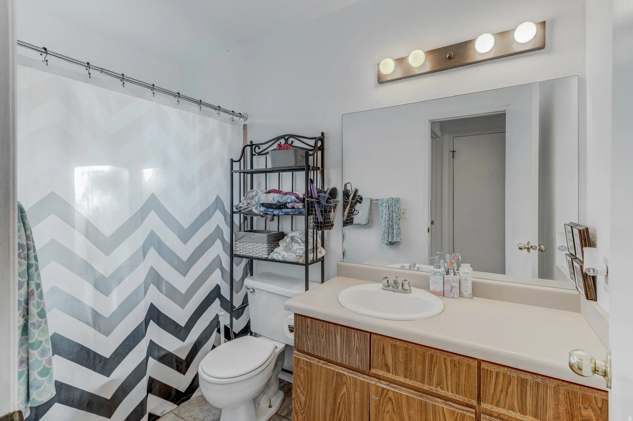 Vanity with wood-finish cabinetry, integrated sink, and light-colored countertop