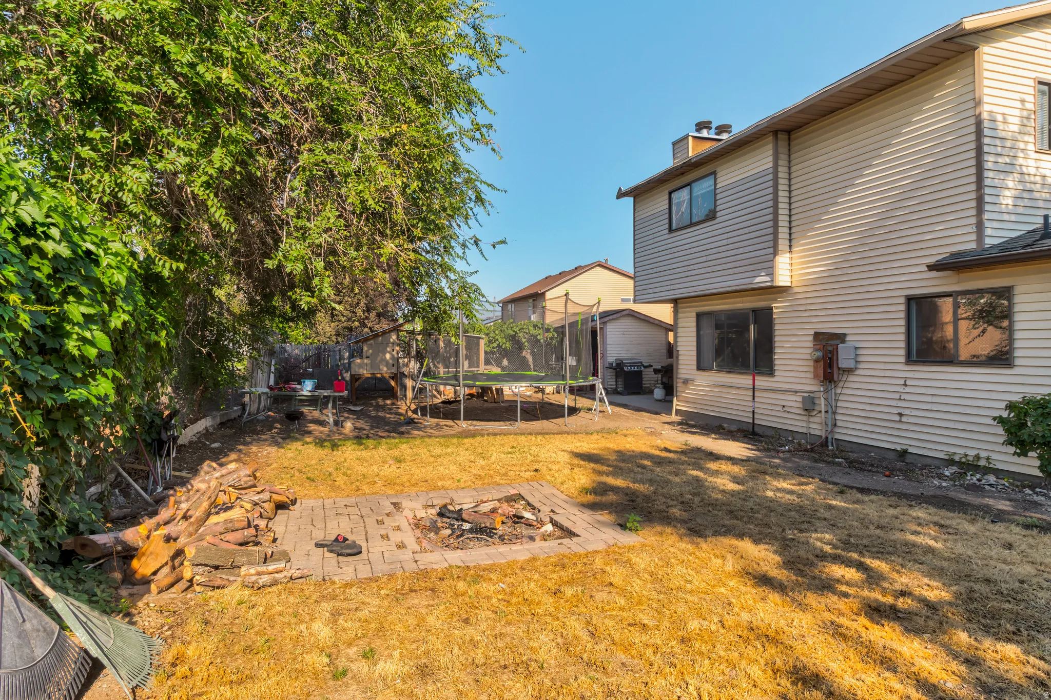 Backyard featuring a brick fire pit, wood siding exterior, and mature trees