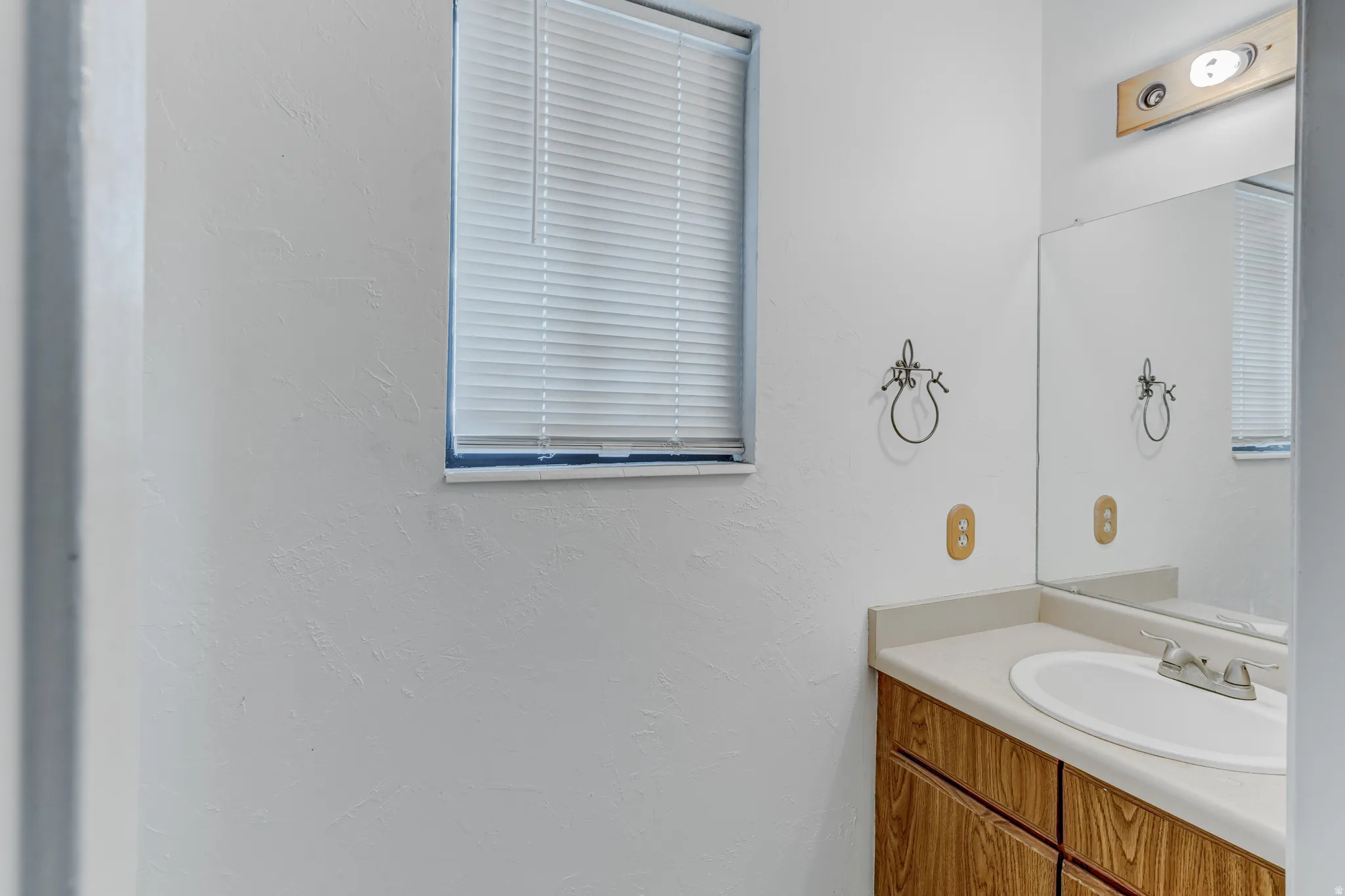 Vanity with wood-finish cabinetry, integrated sink, and light-toned countertop
