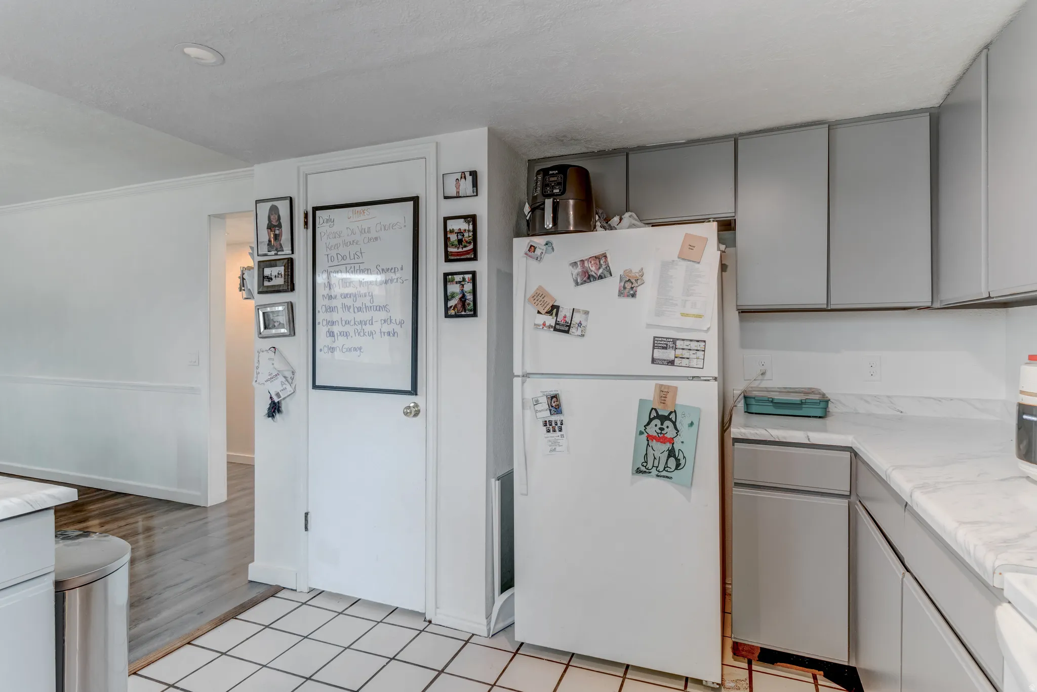 Kitchen featuring white tile flooring, gray cabinetry, and white countertops