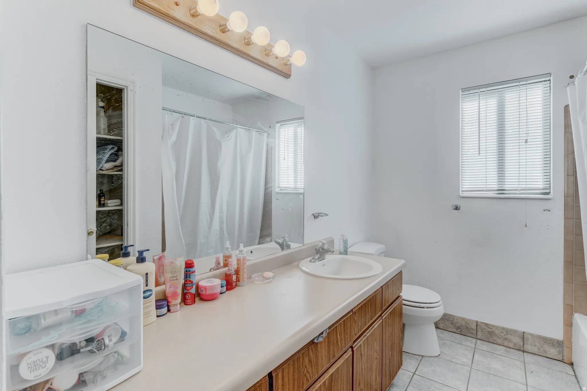 Vanity with integrated sink, wood-finish cabinetry, and a full-width mirror