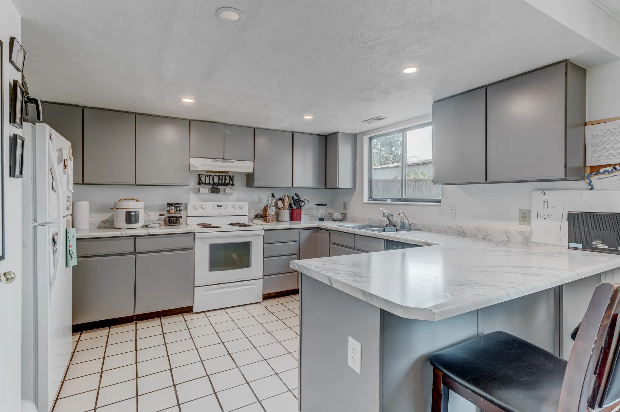 U-shaped kitchen featuring grey cabinetry, white tile flooring, white appliances, and light-toned countertops
