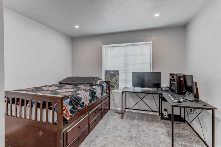 Recessed lighting, window with blinds, light gray wall finish, gray carpet flooring, wood-finish bed frame with built-in storage drawers