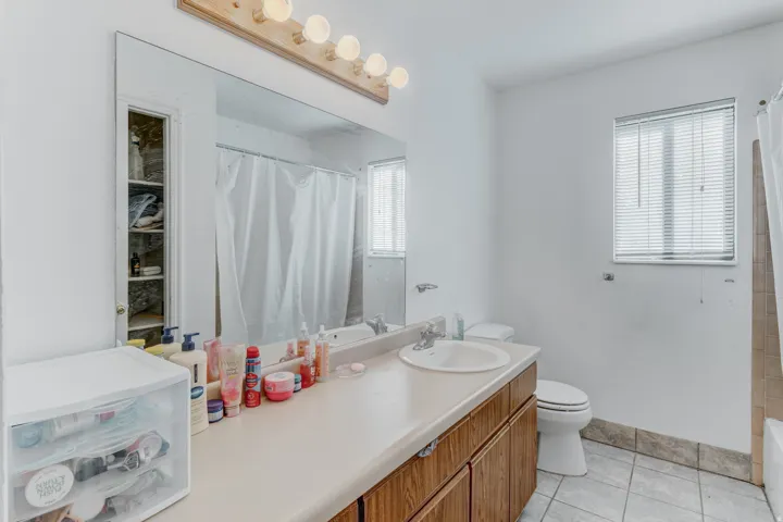 Vanity with integrated sink, wood-finish cabinetry, and a full-width mirror