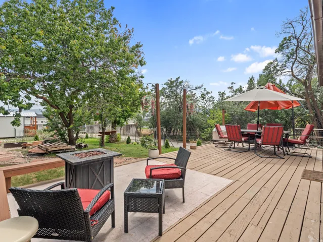 Expansive outdoor living area featuring a wood-finish deck, a concrete patio, and a dedicated fire pit area