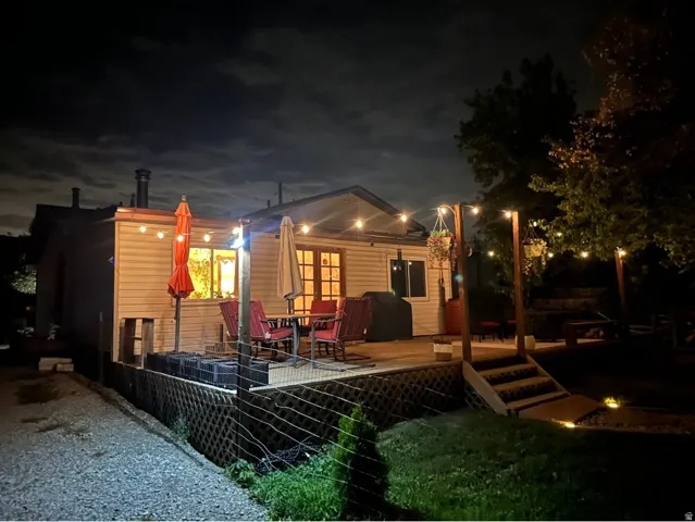 Wood-tone decking with lattice skirting, illuminated by string lighting