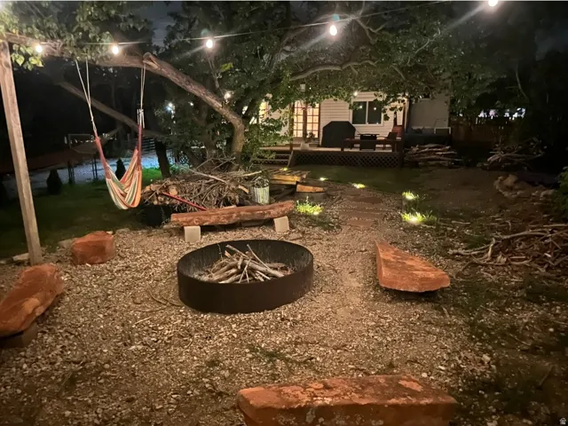 Gravel patio with a fire pit, string lighting, and stone seating