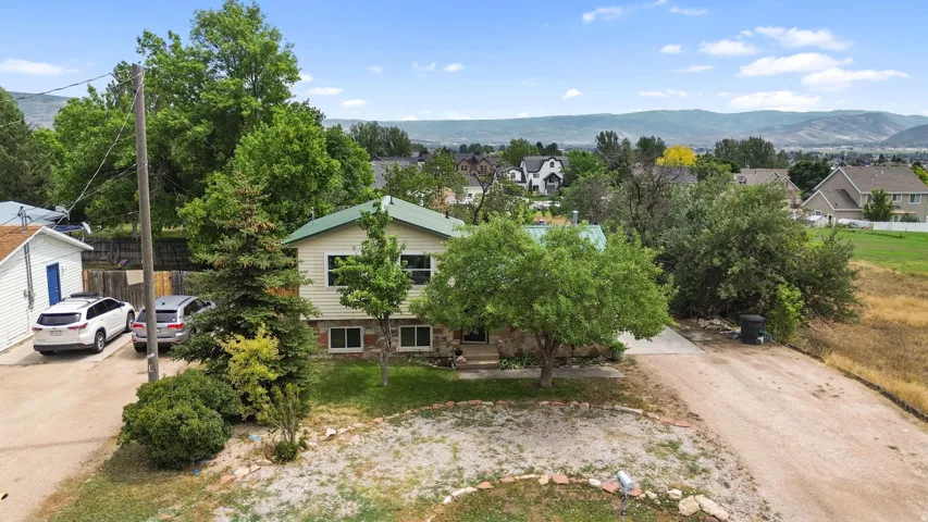 Property with a green metal roof, stone facade, and mature trees