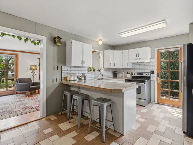 Kitchen featuring white cabinetry, subway tile backsplash, stainless steel appliances, and a breakfast bar