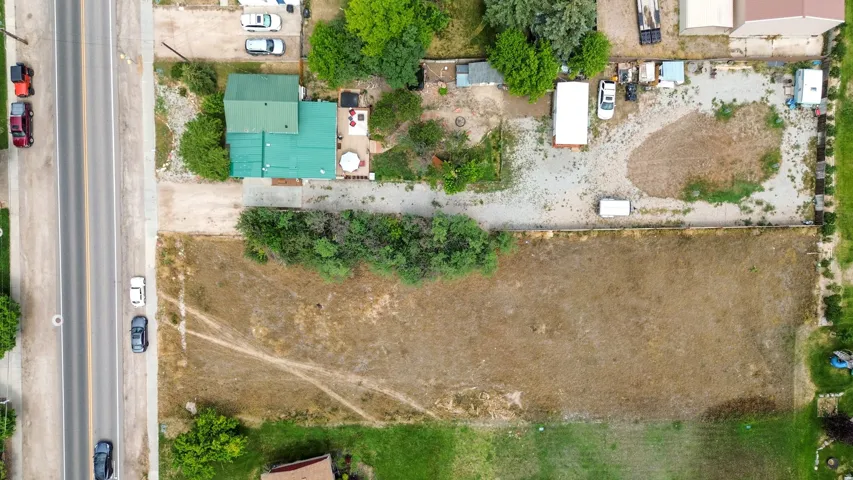 Expansive property featuring a two-story residence with a green roof, a gravel driveway, and a large undeveloped land parcel