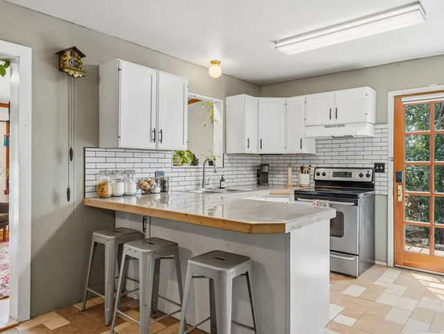 Kitchen featuring white cabinetry, subway tile backsplash, stainless steel range, and a breakfast bar with solid surface countertops