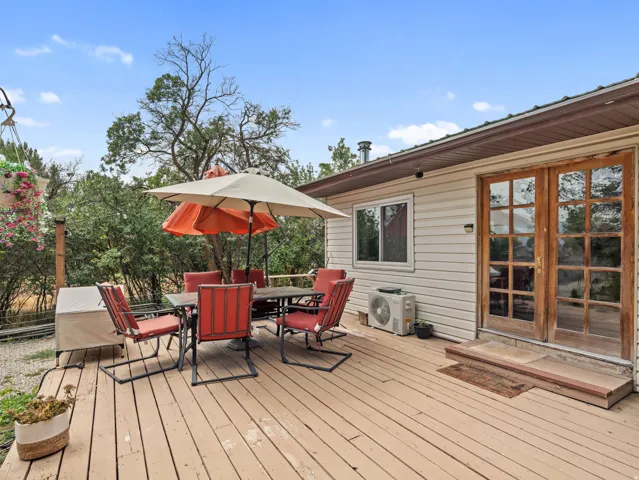 Wood-finish deck with a vinyl-sided exterior, clear-paned double doors, and a single window