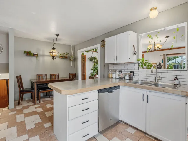 Kitchen featuring white cabinetry, subway tile backsplash, stainless steel dishwasher, and a double basin sink