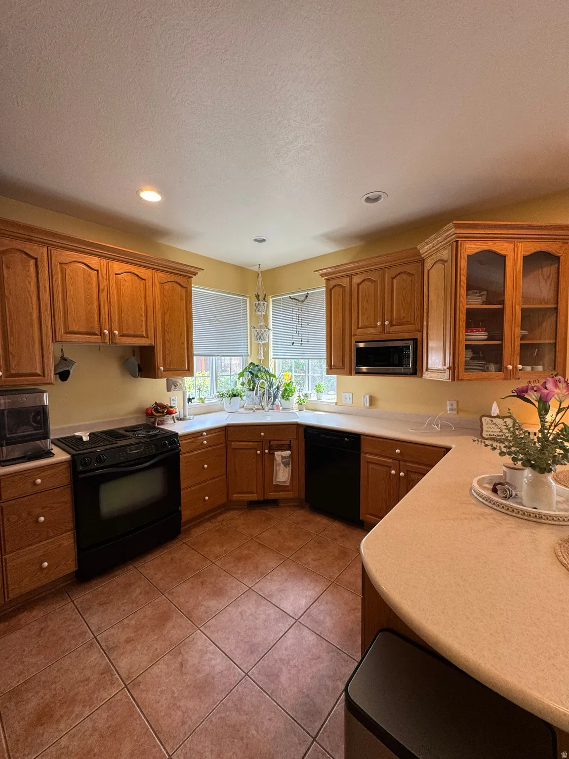 U-shaped kitchen layout with wood-finish cabinetry, tile flooring, and a corner window