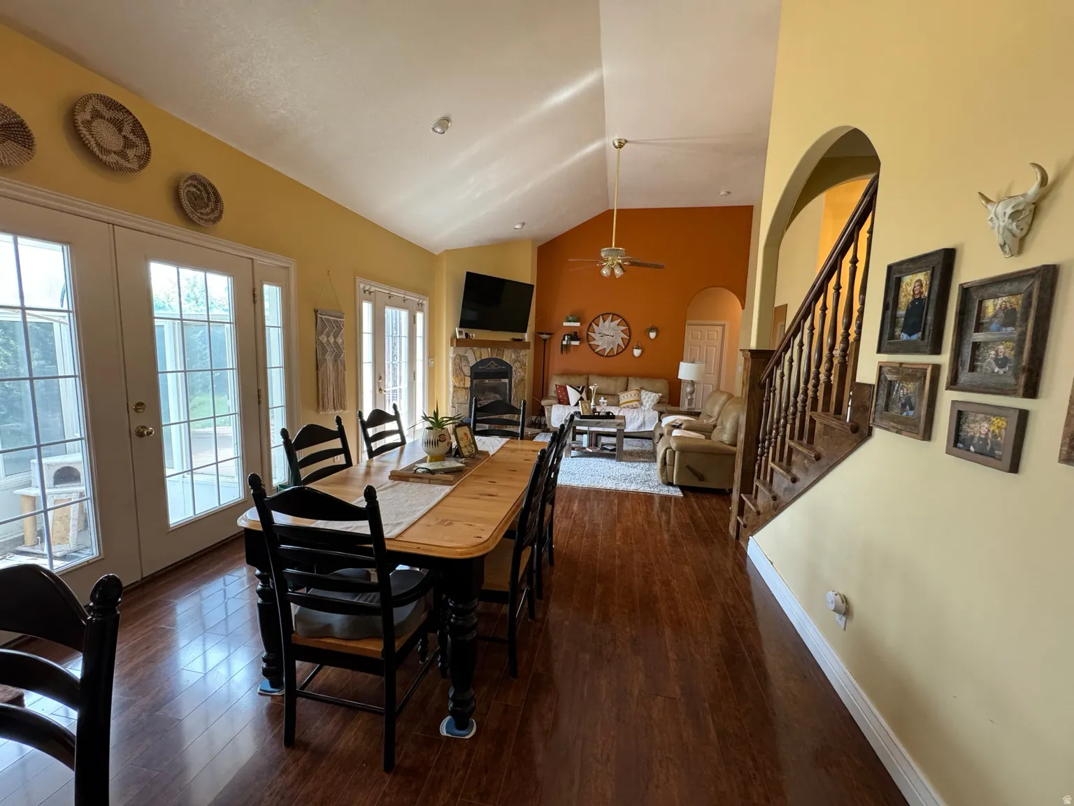 Spacious living area featuring high vaulted ceilings, rich wood-finish flooring, and a prominent stone fireplace