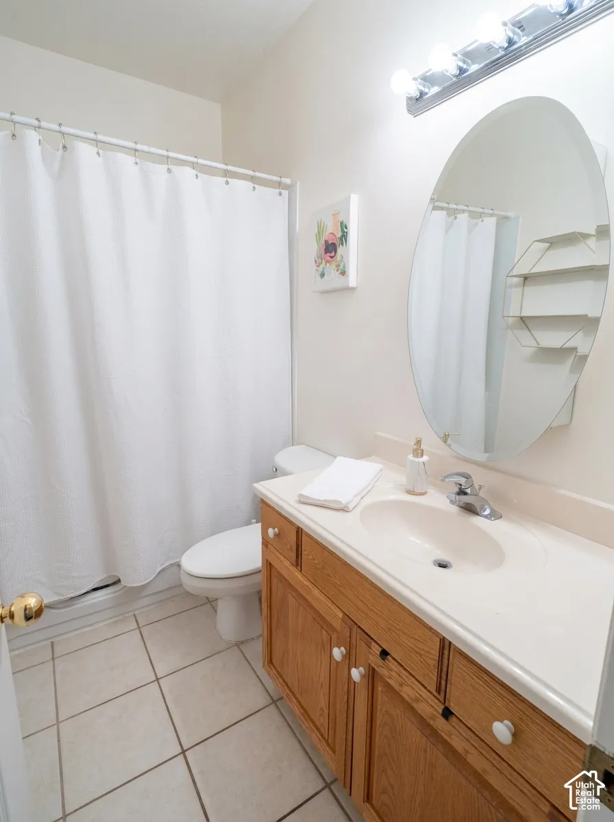 Wood-finish vanity with a single basin sink, oval mirror, and tile flooring