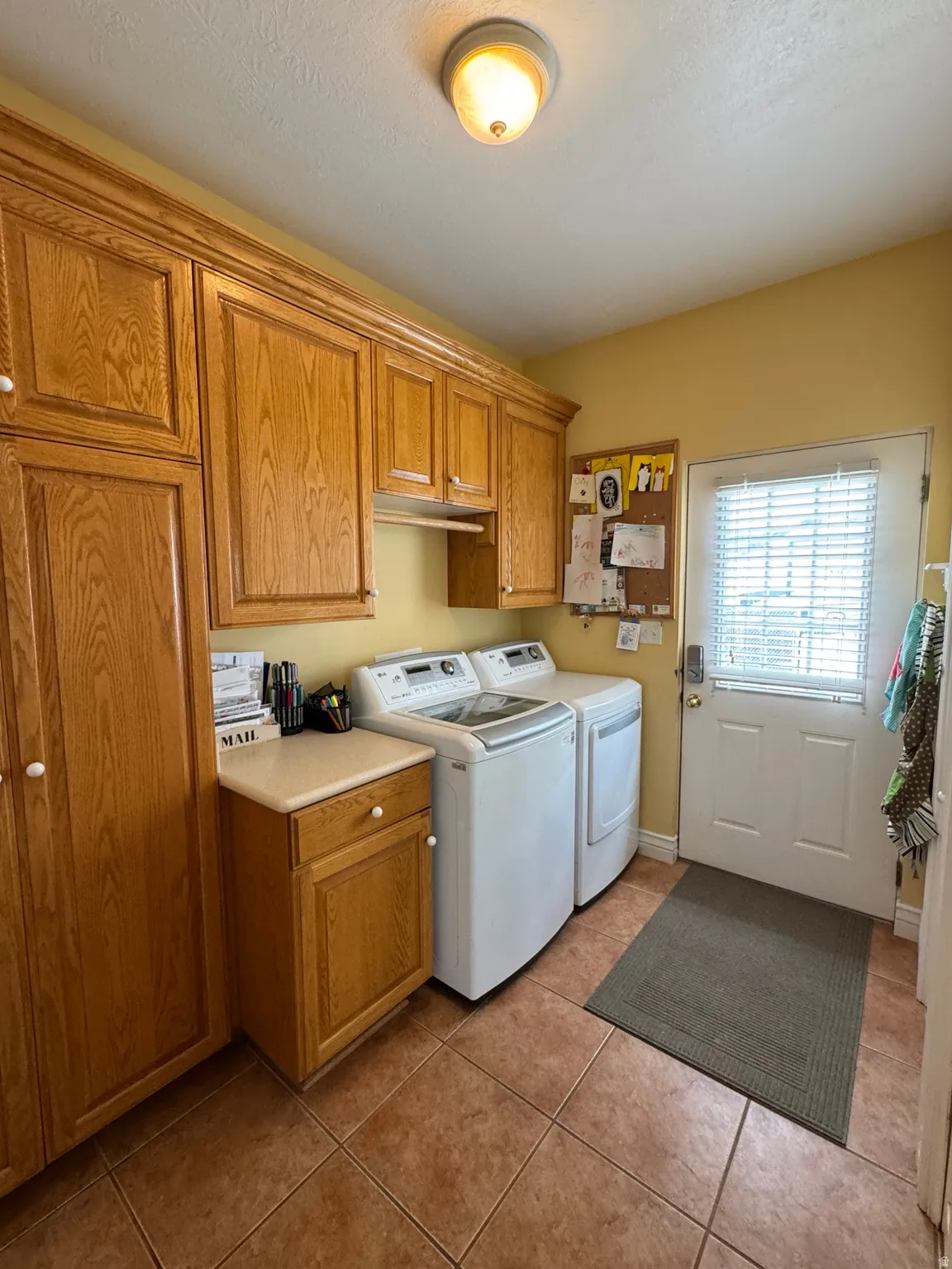 Laundry room featuring extensive wood-finish cabinetry, a built-in counter, and tile flooring