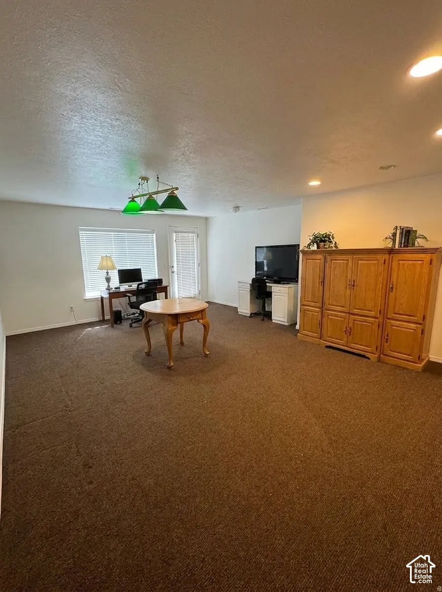 Spacious room featuring brown carpeting, a window with blinds, and a glass-paneled door