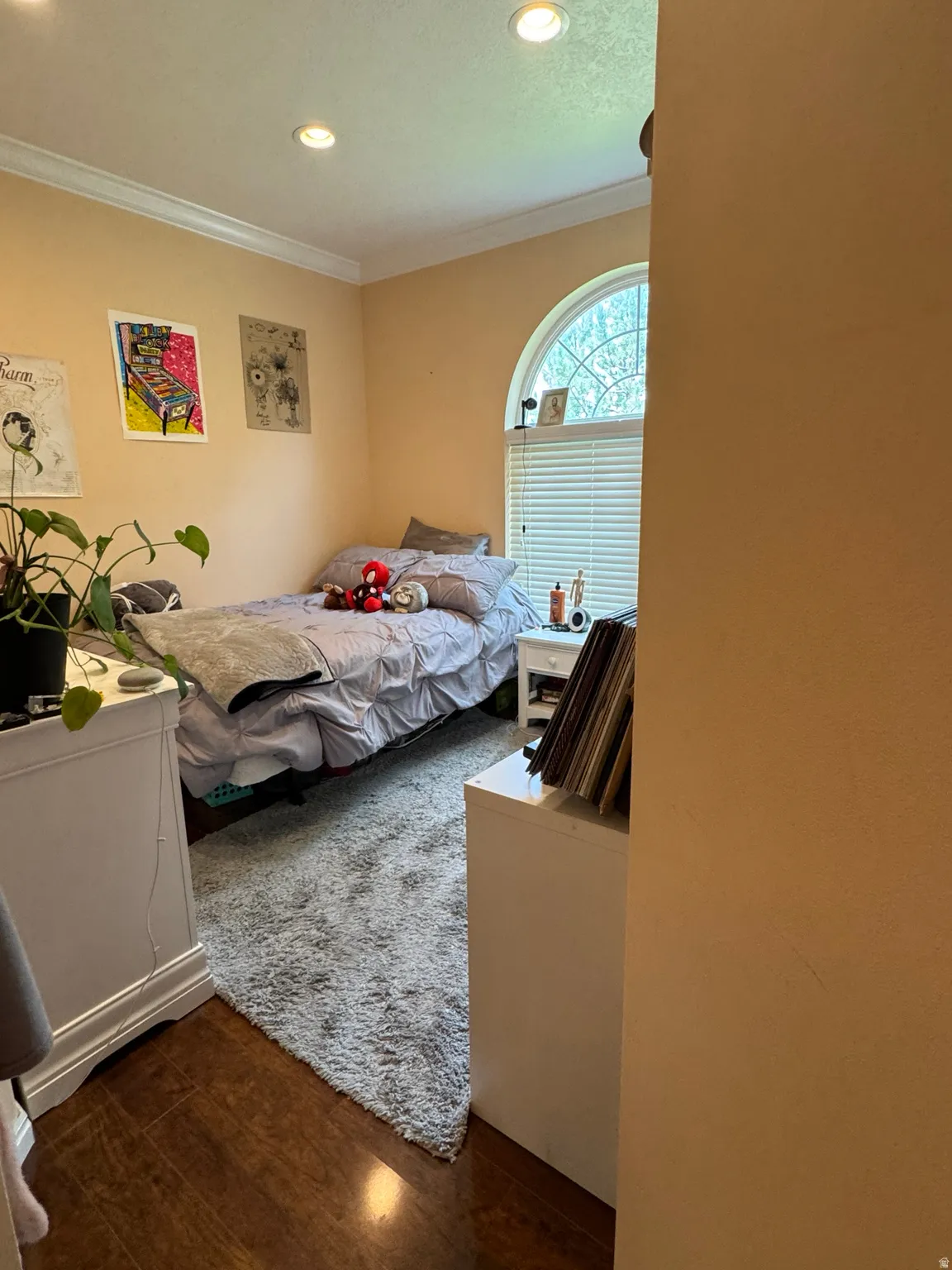Arch-top window with blinds, recessed lighting, crown molding, wood-finish flooring, and a light-toned wall finish