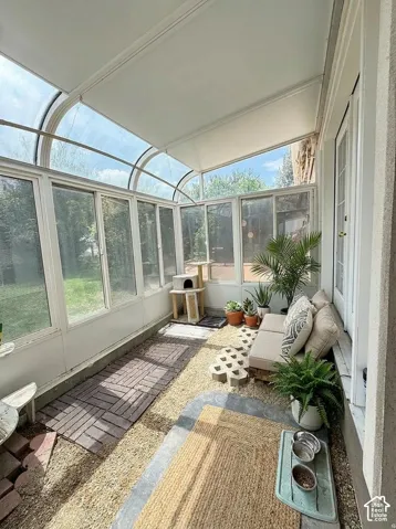 Sunroom featuring a curved glass roof, extensive window panels, gravel flooring, and brick paver accents