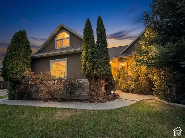 Stucco exterior, arched window, mature landscaping, concrete pathway, exterior lighting