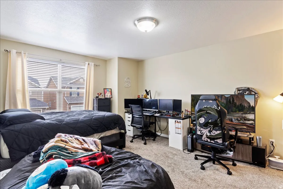 Carpeted room with a ceiling-mounted light fixture, and window with blinds