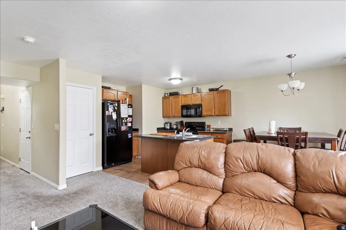 Open-concept living space featuring a kitchen island, wood cabinetry, recessed lighting, and a dining area with a chandelier